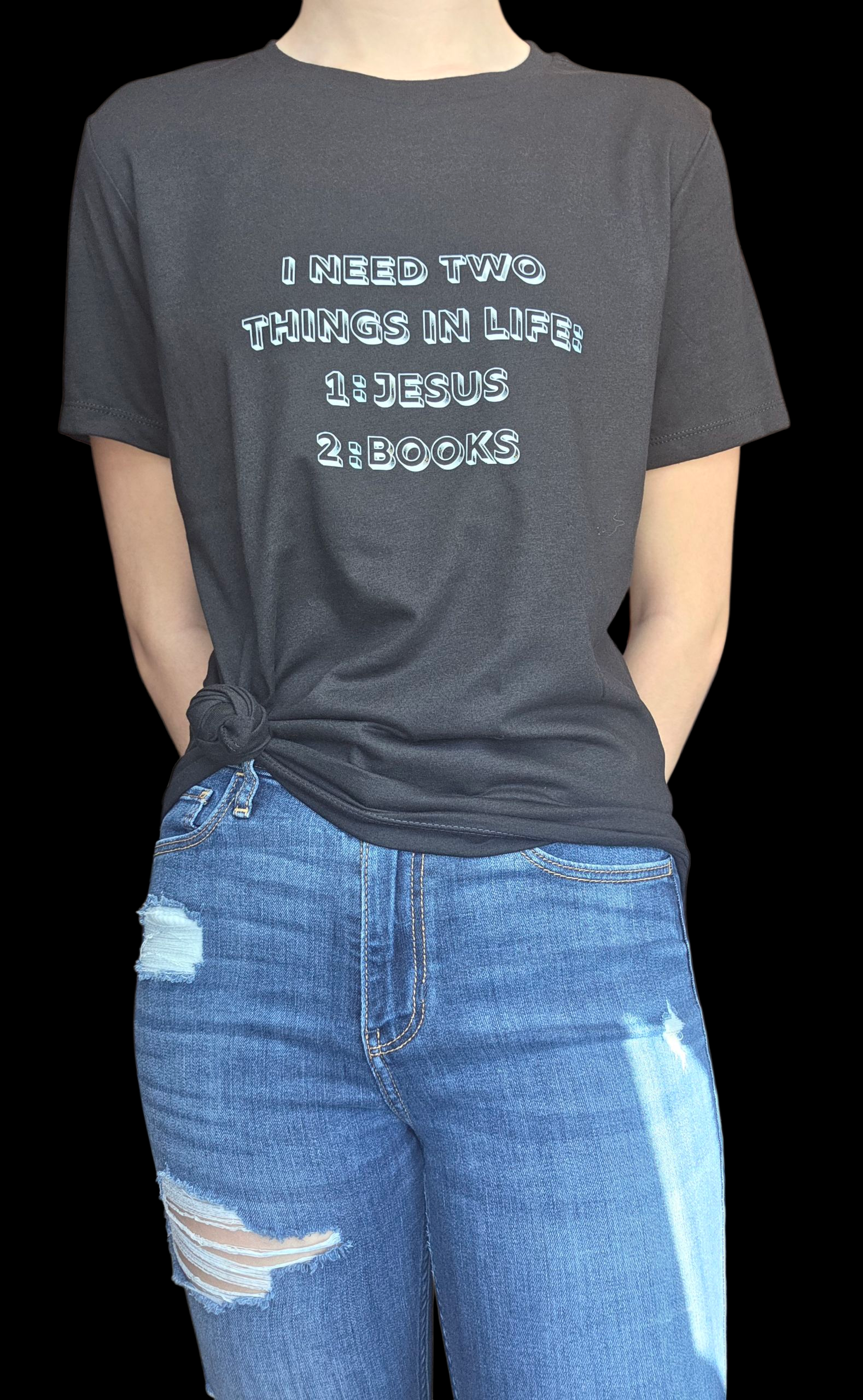 Person wearing a black t-shirt with text and blue jeans on a black background