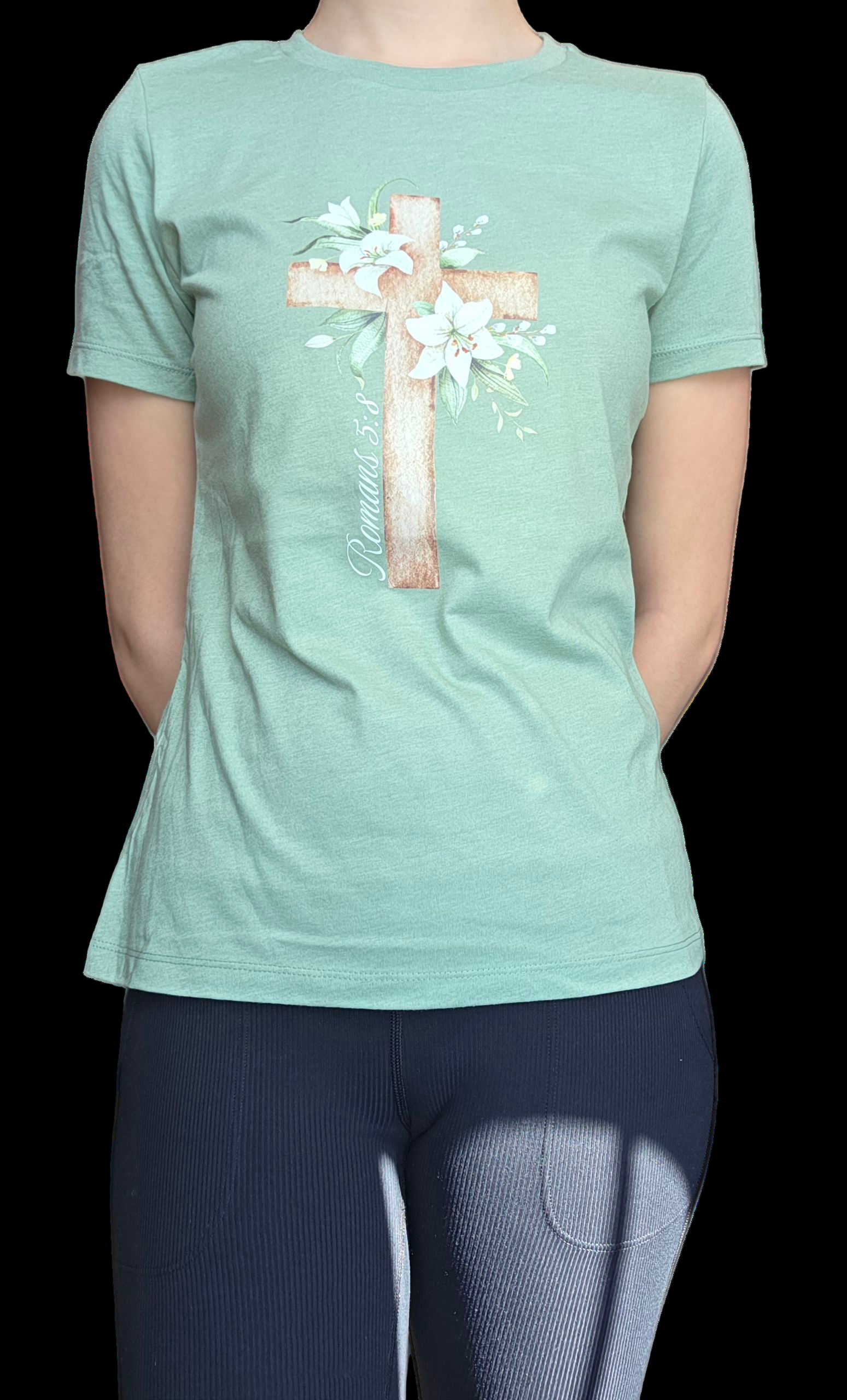 Person wearing a light green t-shirt with a cross and floral design on a black background