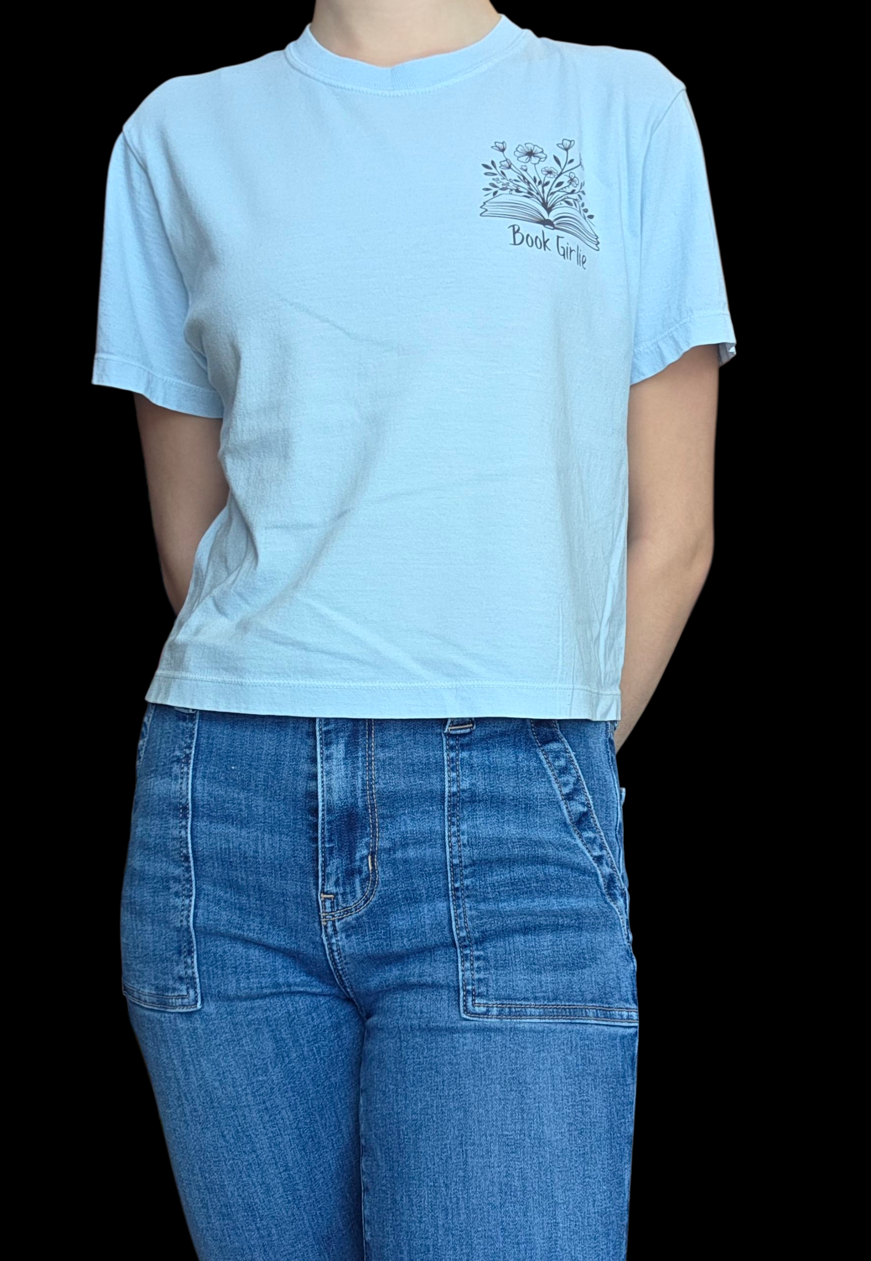 Person wearing a light blue t-shirt with a graphic design and text, standing against a black background