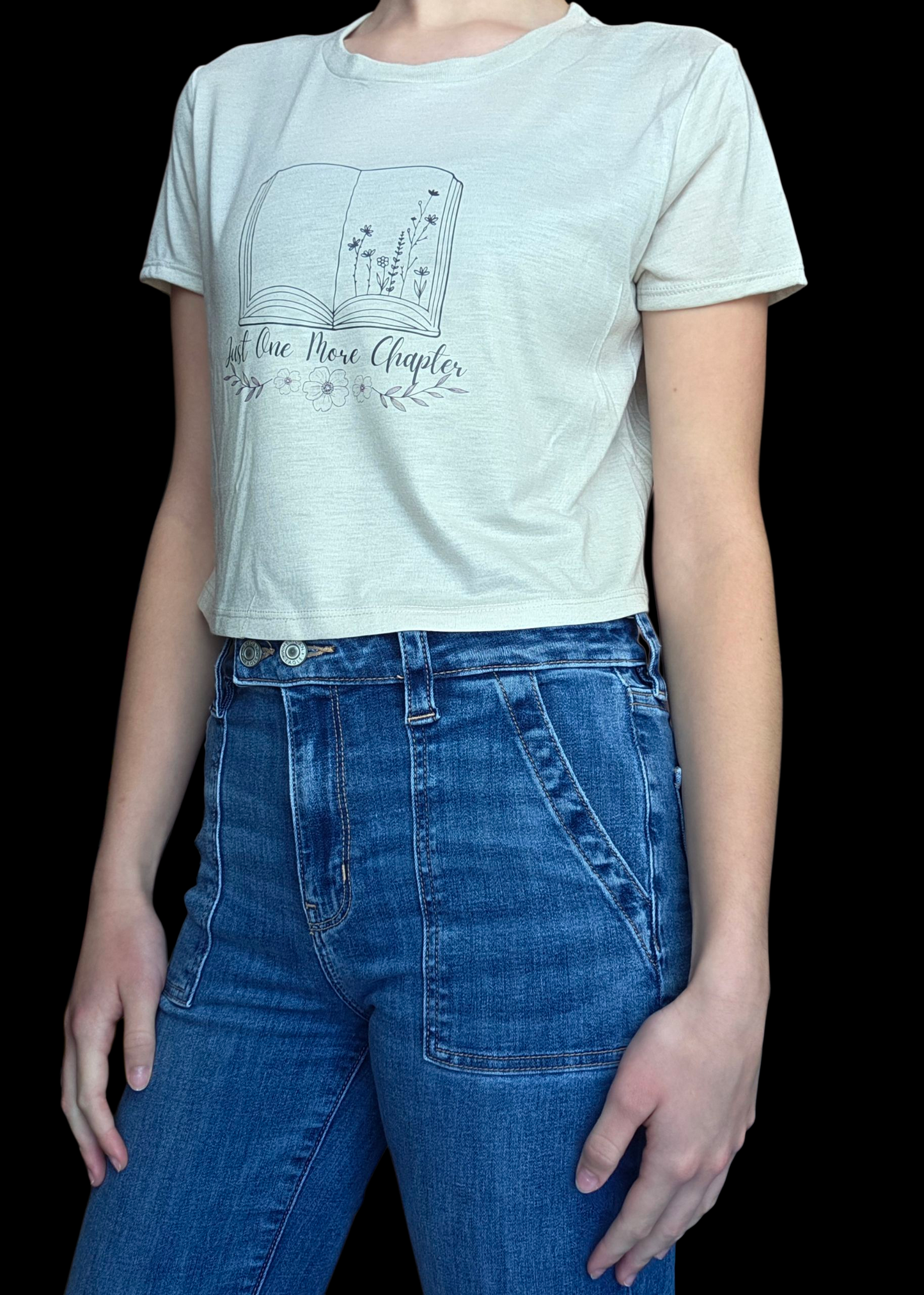 Person wearing a beige t-shirt with a graphic design and blue jeans on a black background